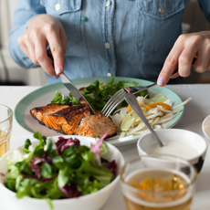 Woman eats a salmon fillet with mixed salad